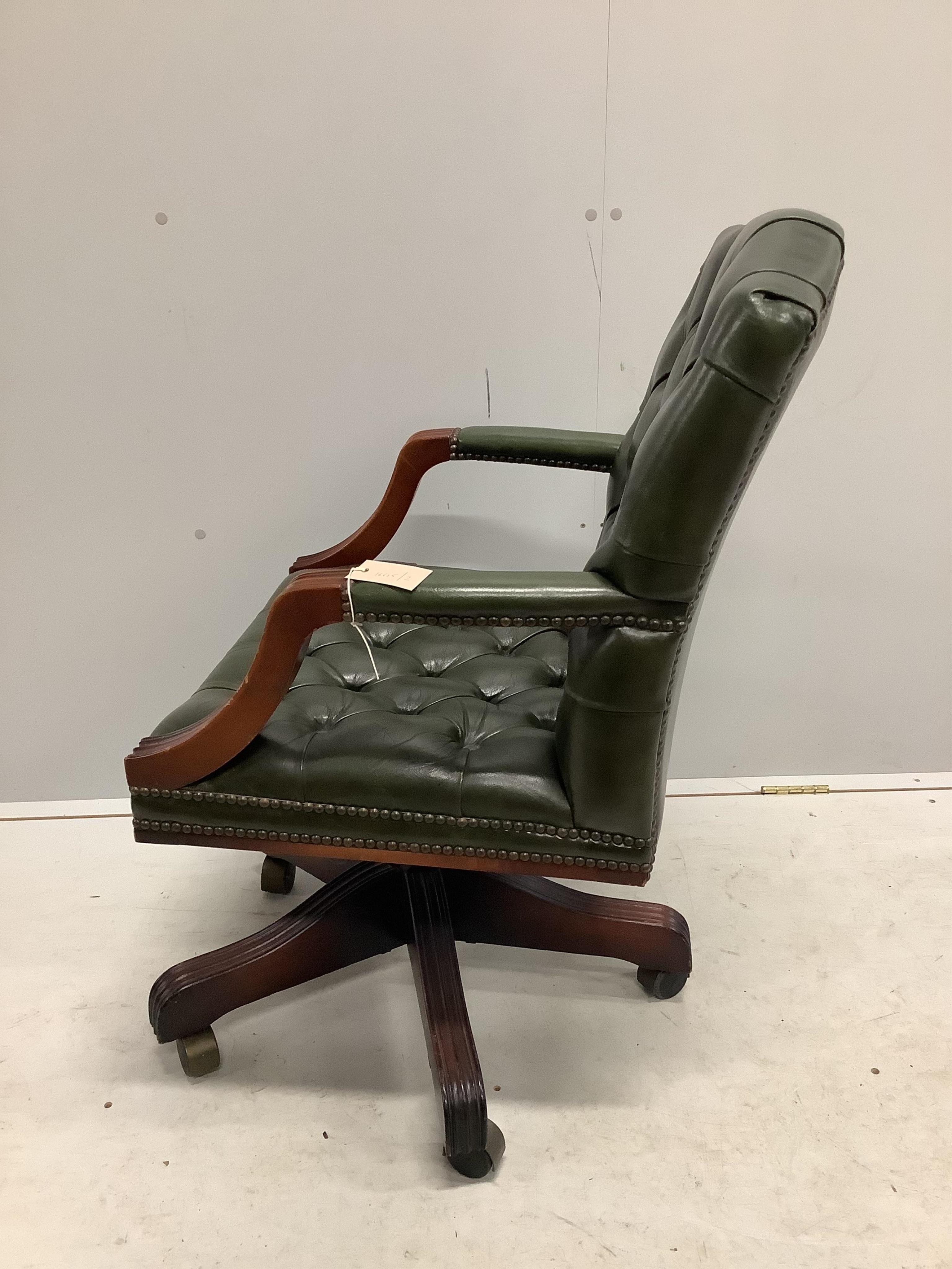 A reproduction mahogany and buttoned green leather swivel desk chair, width 56cm, depth 50cm, height 92cm. Condition - fair